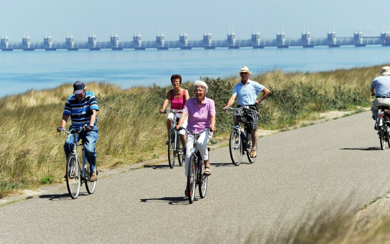 Mensen fietsen in Zeeland langs het water.